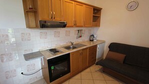 A compact kitchen with wooden cabinets, a built-in oven, a sink, and a small refrigerator.