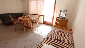Une pièce confortable avec une table à manger, des chaises, un canapé, un téléviseur et une fenêtre avec des rideaux.