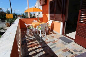 Un espace extérieur aménagé avec une table et des chaises, un sol carrelé et un panneau indiquant les directions pour se rendre aux lieux d’intérêt à proximité.