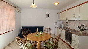 Cocina compacta con zona de comedor, que incluye una mesa redonda de madera, sillas, un refrigerador pequeño y una cafetera.