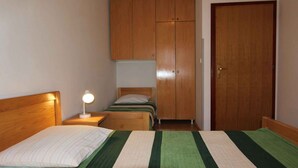 Un dormitorio con cama, mesita de noche, lámpara, armario y una puerta.