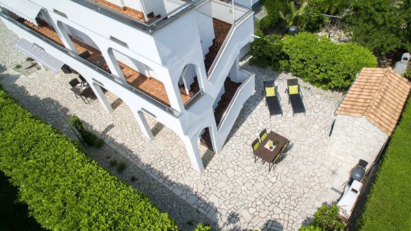 A modern building with a rooftop terrace featuring outdoor seating and a small table.