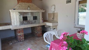 An outdoor kitchen with a brick chimney, a sink, and a window.