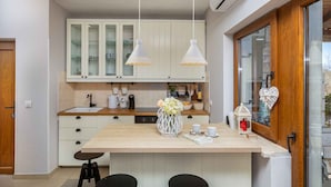 Una cucina moderna con mobili bianchi, un piano di lavoro in legno e lampade a sospensione.