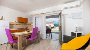 A modern kitchen with a wooden table and chairs, a dining area with a view through a glass door, and a living area with a sofa and a lamp. - Studio with pool for 6 people (Malinska)