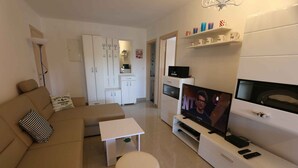 A modern living room with a sofa, a small table, a TV, and a cabinet. - Holiday apartment with balcony and air conditioning (Šilo)