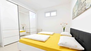 A bedroom with a bed, a wardrobe, a small window, and a painting on the wall.