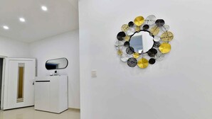 A modern interior with a white reception desk, a wall-mounted mirror, and a decorative metal wall art piece.