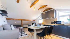 Een moderne keuken met donkere kasten, een houten plafond en een eethoek met een tafel en stoelen.