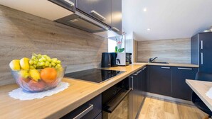 Een moderne keuken met donkere kastjes, een houten aanrechtblad en een schaal met fruit.