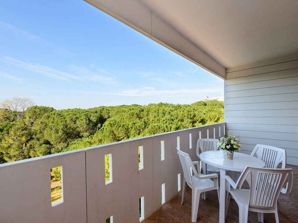 Un balcone con tavolo e sedie, vista su una zona boschiva.