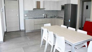 Una cocina moderna con armarios blancos, encimera de granito y refrigerador de acero inoxidable.
