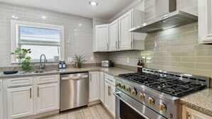 Una cocina moderna con armarios blancos, electrodomésticos de acero inoxidable y una ventana con vistas.