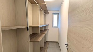 A narrow hallway with wooden shelving units and a door on the right.