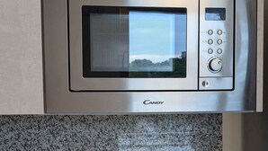 A kitchen with a microwave, coffee maker, and kettle.