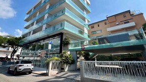 Un immeuble à plusieurs étages doté d’une façade en verre, d’un panneau indiquant un parking et d’un passage piétonnier aérien.