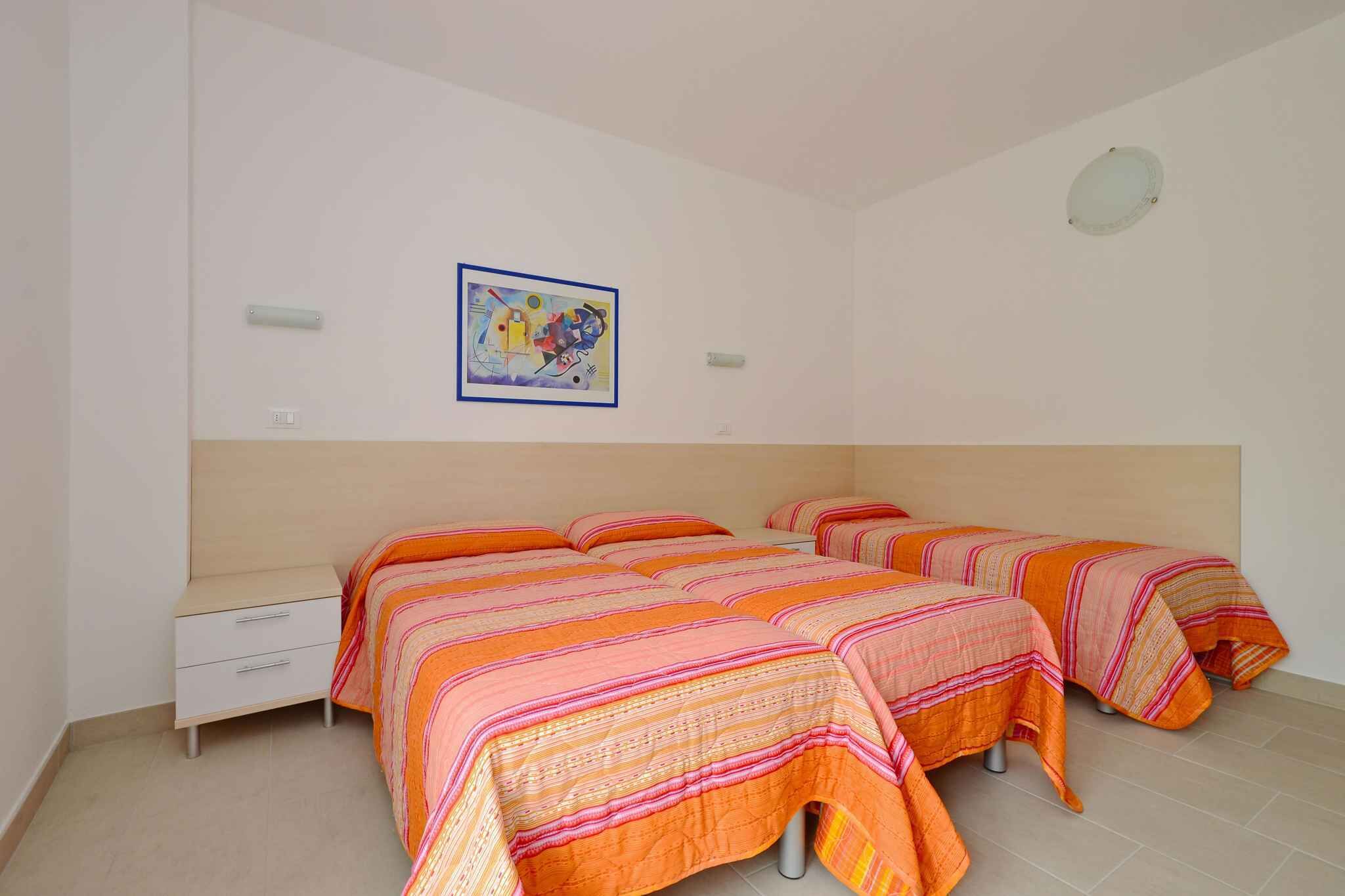 Une chambre avec deux lits, une table de chevet et un luminaire fixé au mur.