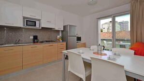 Une cuisine moderne avec des meubles blancs, un four à micro-ondes, un réfrigérateur et un coin repas comprenant une table et des chaises.