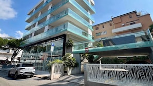 Un immeuble à plusieurs étages doté d’une façade en verre, d’un panneau indiquant un parking et d’un passage piétonnier aérien.