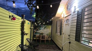 A cozy outdoor patio with a dining area, string lights, and a mural. - Tiny Wooden Home in Vega Baja with pool and close to the beach (Vega Baja)