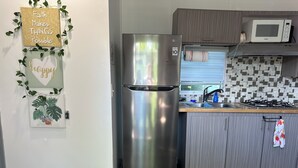 A modern kitchen with a stainless steel refrigerator, a microwave, and a tiled backsplash. - Tiny Wooden Home in Vega Baja with pool and close to the beach (Vega Baja)