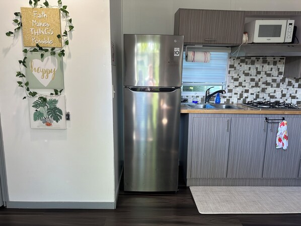 Una cocina moderna con refrigerador de acero inoxidable, microondas y salpicadero de azulejos.