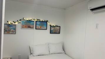 Un dormitori amb un llit, una tauleta de nit i tres quadres al mur.