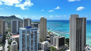 A high-rise hotel with multiple floors, a view of the ocean, and a mountainous backdrop. - Comfortable King Bed Waikiki Studio 2 mins walk to Beach with WiFi & AC (Honolulu)
