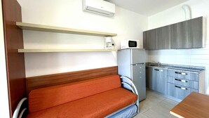 Una cocina compacta equipada con microondas, refrigerador y un banco de madera.