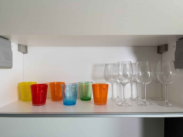 Ein Regal mit bunten Plastikbechern und Weingläsern.
