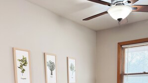 A dining area with a round wooden table, two chairs, and a ceiling fan. There are three framed botanical illustrations on the wall. - 146 Wedgewood Wonder - Charming 2 bed 1 bath (Lincoln)