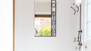 A clean, white hallway with a bench and three wicker baskets underneath. - Morgensonne by Interhome (Karlshagen)