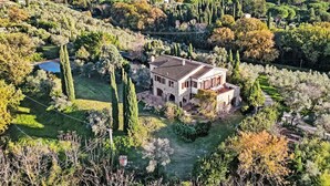 A large, two-story stone house surrounded by a well-maintained garden with tall trees and a small pond. - Tramonto by Interhome (Guardistallo)