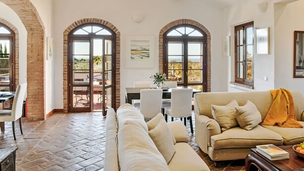 A spacious living room with a large sofa, a dining area, and a view through arched windows. - Tramonto by Interhome (Guardistallo)