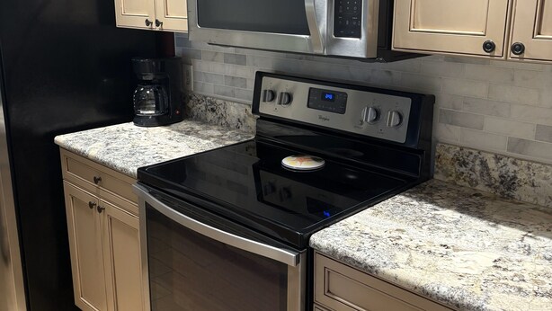 A kitchen with a stainless steel microwave, oven, and coffee maker. - "Nothing But Sunshine" (Fort Myers)
