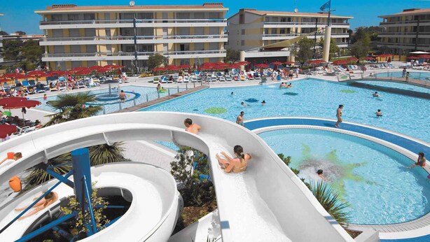 Ein Resort mit mehreren Schwimmbecken, einer Wasserrutsche und einem Gebäude mit Balkonen.