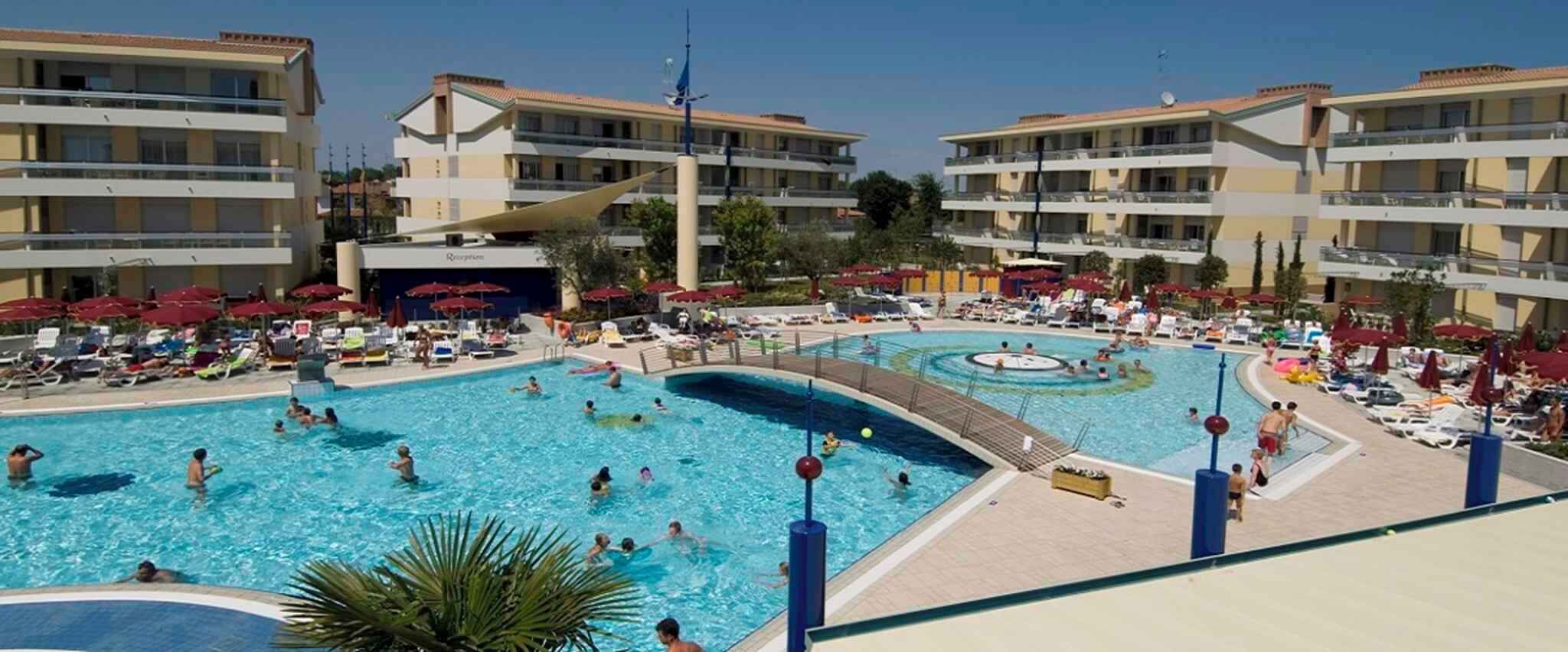 Un hôtel doté d’une grande piscine, de nombreux balcons et de chaises longues.