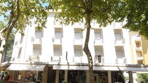 A multi-story building with balconies, a covered entrance, and a small outdoor seating area. - Holiday apartment Close to the thermal baths and only 200 metres from the sea (Bibione)