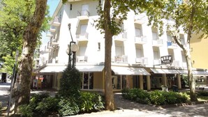 A multi-story hotel with balconies, a poker sign, and a well-maintained garden area. - Holiday apartment Close to the thermal baths and only 200 metres from the sea (Bibione)
