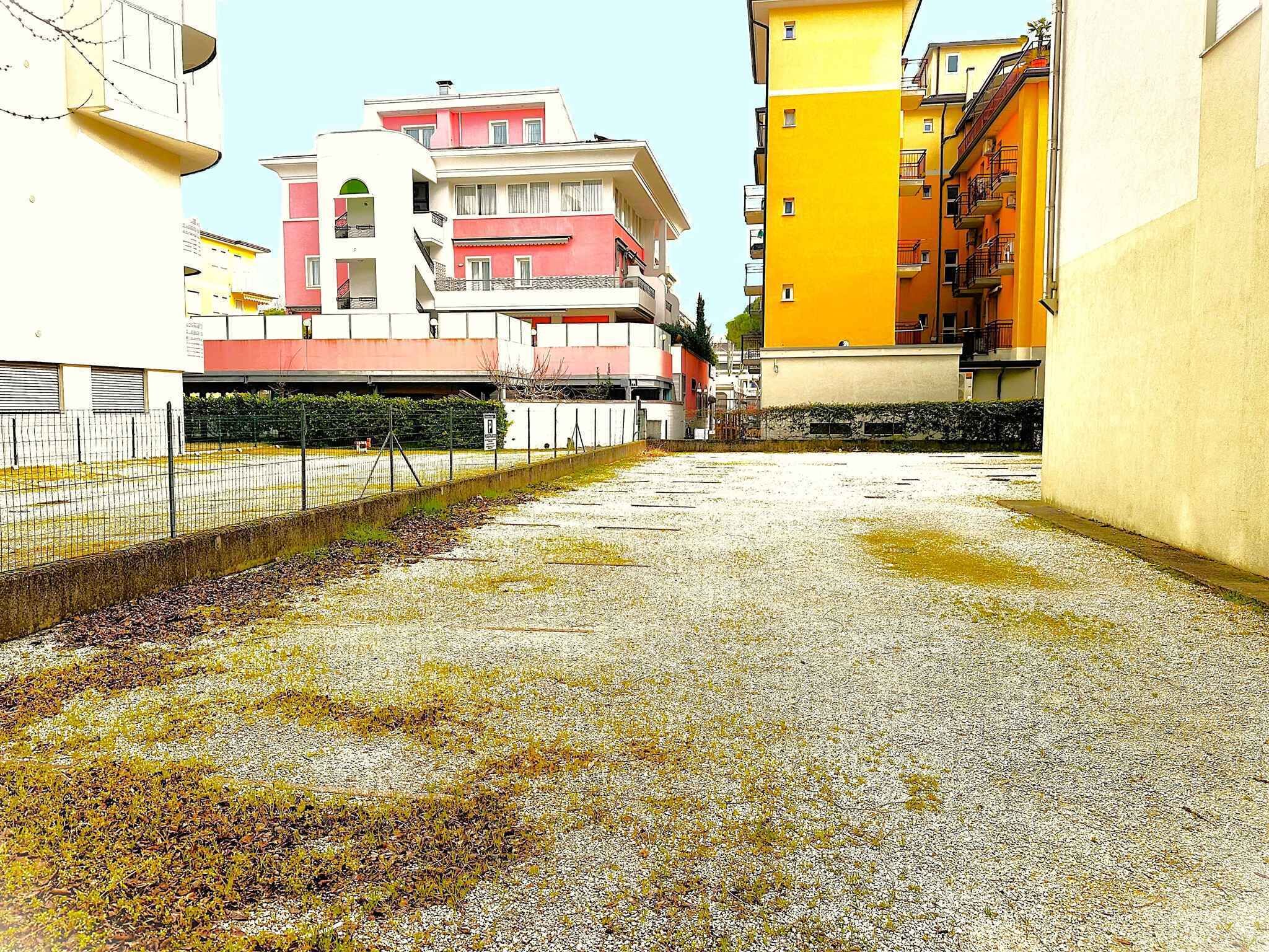 A courtyard with a gravel ground, a fence, and buildings with balconies.