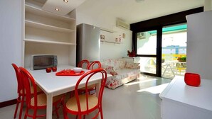 A compact living space with a dining area, kitchenette, and a sofa.
