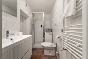 Une salle de bain équipée d’une douche, de toilettes, d’un lavabo et d’un porte-serviettes.