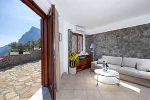 Une pièce avec un sol en pierre, un canapé, une table basse, un meuble et une vue sur les montagnes.