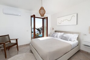 Un dormitorio con cama, una silla, una lámpara colgante, una ventana y un aire acondicionado instalado en la pared.