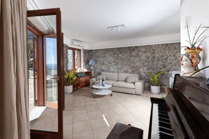 Un salón con un piano, un sofá, una mesa de centro y una pared de piedra.