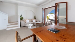 Un interior moderno con una mesa de comedor de madera, un sofá y una escalera que sube a un nivel superior.