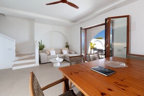 Un interior moderno con una mesa de comedor de madera, un sofá y una escalera que sube a un nivel superior.