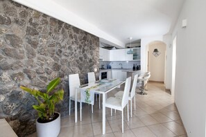 Una cocina moderna con armarios blancos, una mesa de comedor con sillas y una planta en maceta.