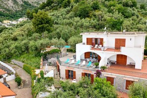A two-story building with a pool, surrounded by greenery and hills. - My Exclusive Italy - Sunlit Villa with unique pool & directly view of Nerano Bay (Nerano)