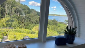 A room with a large arched window overlooking a lush landscape and a body of water.